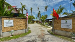 A pathway leading to a property with a stone wall, a signboard, and flags. - Collection O 90622 Sehijau @ Cenang (Langkawi)