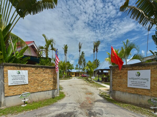 A pathway leading to a property with a stone wall, a signboard, and flags. - Collection O 90622 Sehijau @ Cenang (Langkawi)