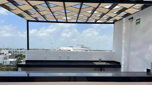 A rooftop terrace with a view of the cityscape, a modern architectural design, and a clear sky.