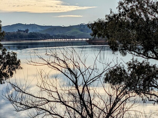 Un puente sobre un cuerpo de agua tranquilo con colinas al fondo.