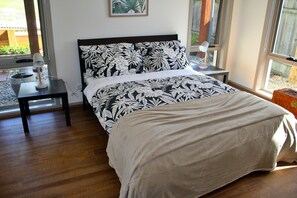 Ein Schlafzimmer mit einem Bett, einem Nachttisch, einer Lampe und einem Fenster.