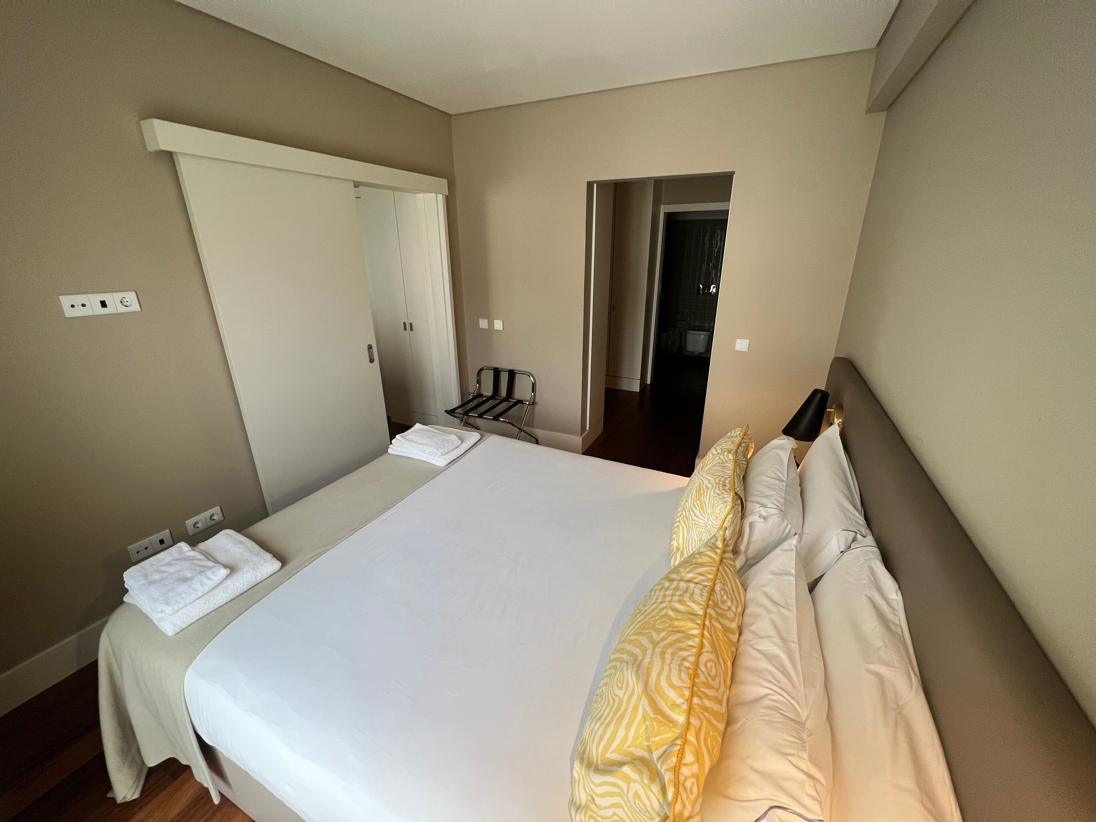 A hotel room with a bed, a desk, a chair, and a wardrobe.