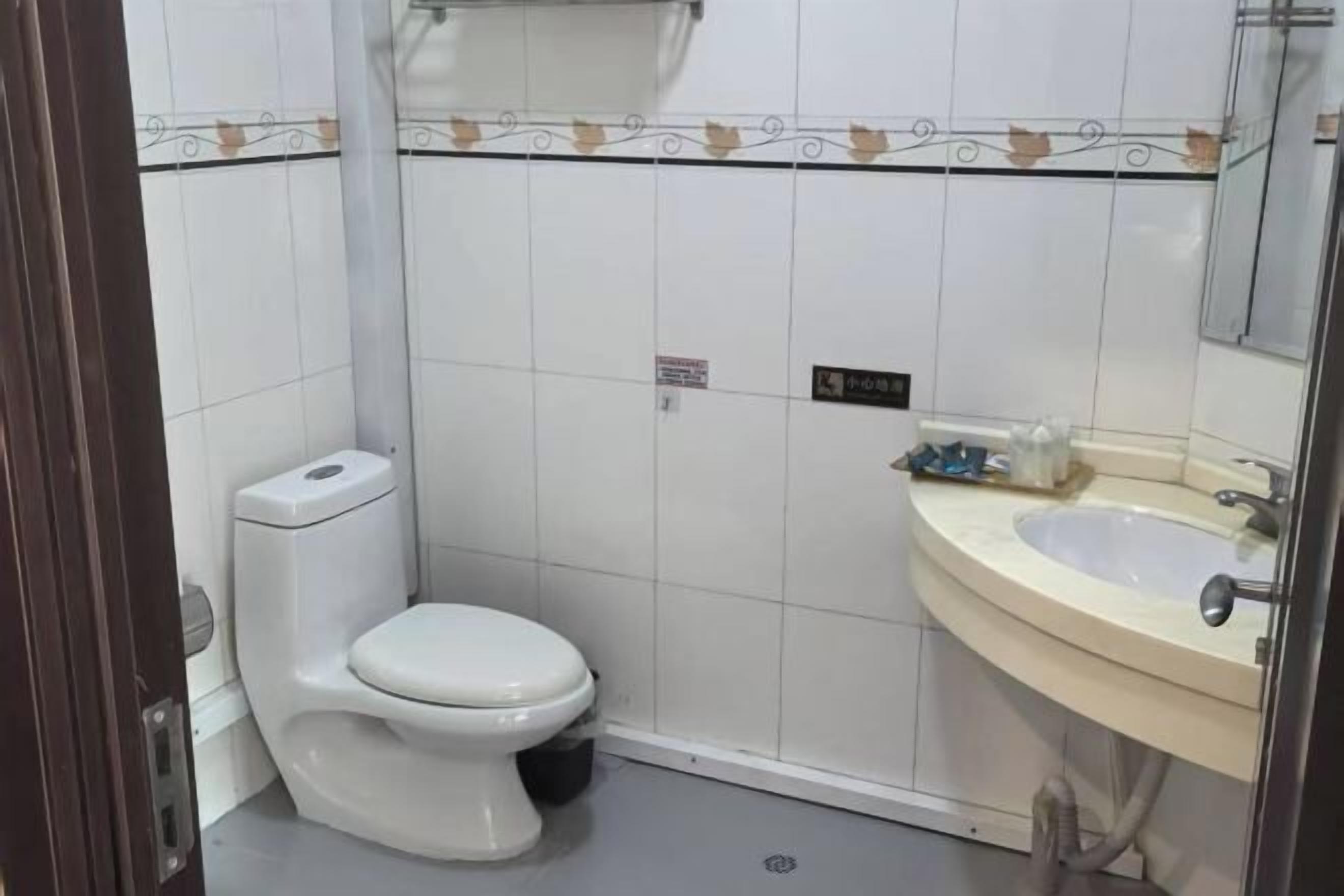 Egy fürdőszoba, amelyben WC, mosdókagyló és tükör található.