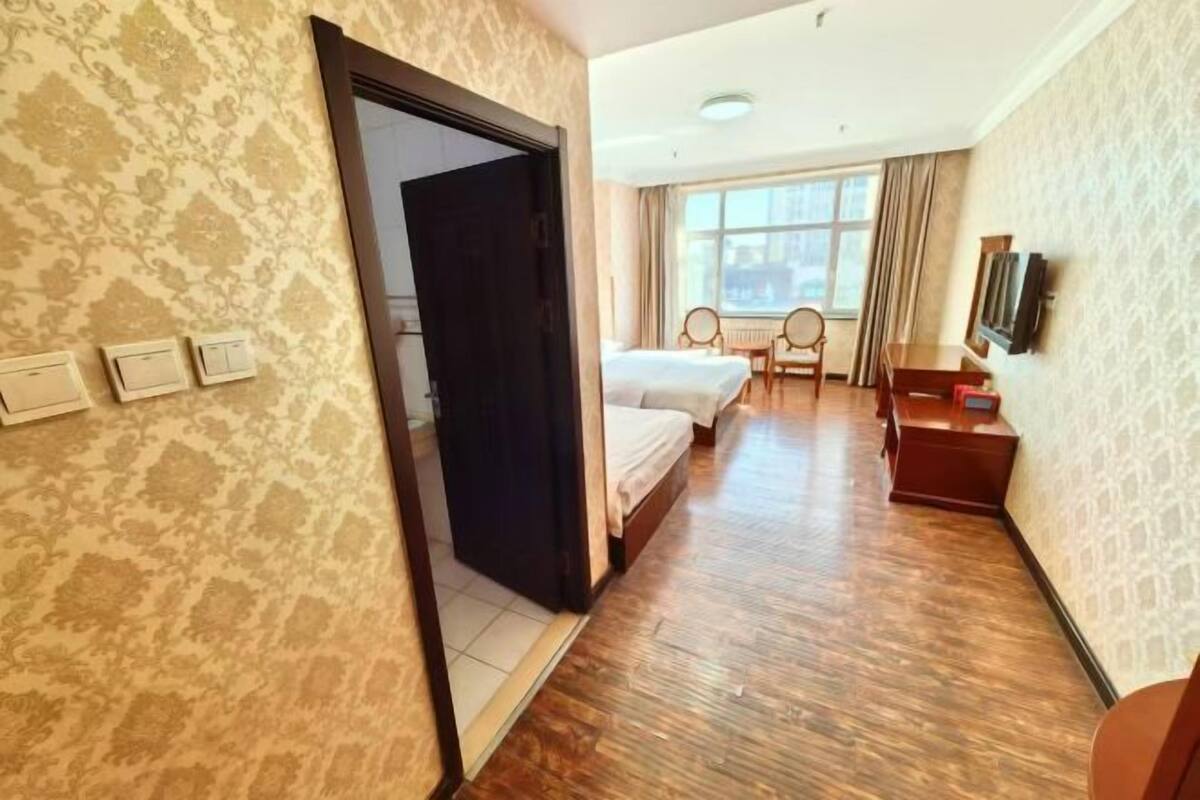 A hotel room with a bed, a desk, a chair, a TV, and a window.