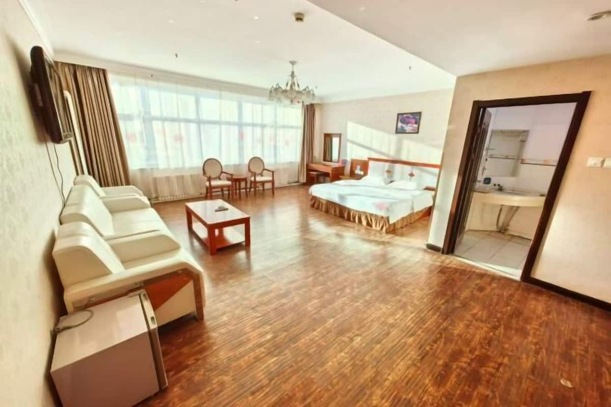 A hotel room with a bed, a sofa, a small table, a TV, and a desk.