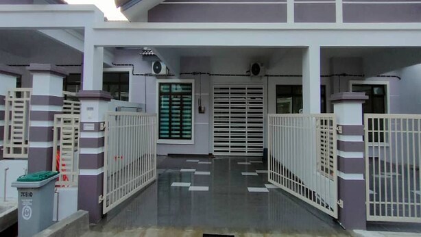 A modern building entrance with a gated driveway, a trash bin, and a security camera. - OYO Homes 90611 Homestay D'emas (Kuala Lipis)
