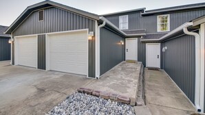 En bostadsbyggnad med två garageportar, en huvudentré och en liten veranda.