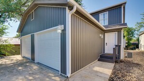 A two-story house with a garage, a front door, and a small porch. - Cheerful Townhouse - Walk to Table Rock Lake! (Kimberling City)