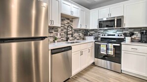 A modern kitchen with stainless steel appliances, white cabinetry, and a tiled backsplash. - Airy Townhome: Close to Kayaking & Boating! (Kimberling City)