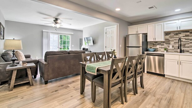 A modern kitchen with white cabinets, a stainless steel refrigerator, and a wooden dining table with chairs. - Airy Townhome: Close to Kayaking & Boating! (Kimberling City)