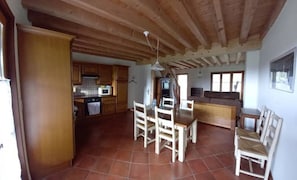 Eine geräumige Küche mit Holzschränken, einem Esstisch mit Stühlen und einem großen Fenster, das für natürliches Licht sorgt.