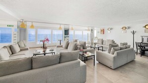 A spacious living area with multiple seating options, large windows offering ocean views, and a clean, modern design. - La Perla del capo hotel (Ospedaletti)