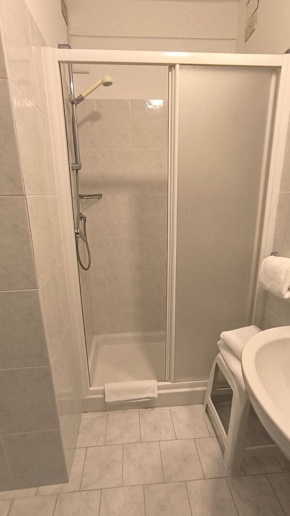A shower with a glass door, a white sink, and a towel rack. - La Perla del capo hotel (Ospedaletti)