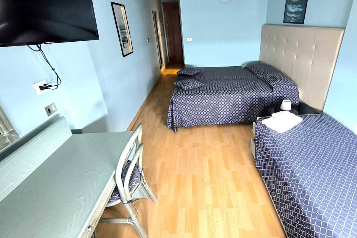 A compact room with two single beds, a small table, and a chair.