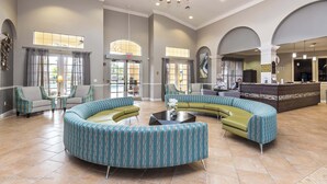 A spacious lobby with a curved seating area, a reception desk, and large windows allowing natural light. - Cozy 3BR Apartment - Vista Cay Resort near Disney! (Orlando)