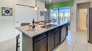 A modern kitchen with granite countertops, stainless steel appliances, and pendant lighting.