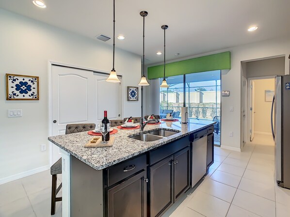 A modern kitchen with granite countertops, stainless steel appliances, and pendant lighting. - Cozy 5-Bedroom Home with Private Pool (Four Corners)