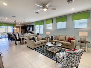 A spacious living area with a dining table, sofas, and a kitchen in the background. - Cozy 5-Bedroom Home with Private Pool (Four Corners)