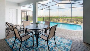 Un patio techado con piscina, mobiliario exterior y vistas al paisaje.
