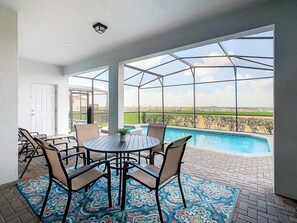 A covered patio area with a pool, outdoor seating, and a view of the landscape.