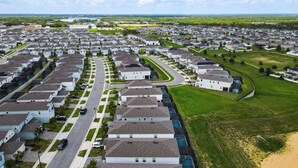 Una zona residencial con casas alineadas, una avenida principal y un extenso campo verde.