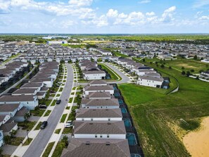 A residential area with houses arranged in rows, a main road, and a large green field.