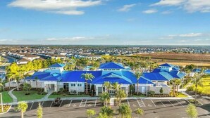 A large building with blue roofs, surrounded by parking and palm trees. - Luxury Home with Private Pool in Davenport (Davenport)