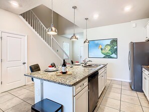 A kitchen with a granite countertop, stainless steel appliances, and pendant lighting.