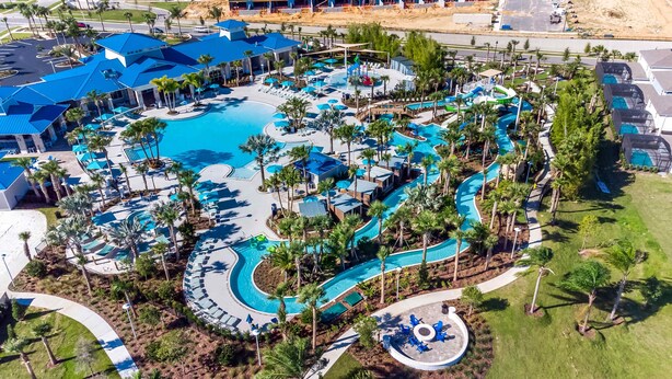 An aerial view of a resort with multiple swimming pools, palm trees, and a parking area. - Luxury Home with Private Pool in Davenport (Davenport)