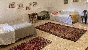 Een kamer met twee bedden, een klein tafeltje en een stoel. Er hangen verschillende prenten aan de muur.