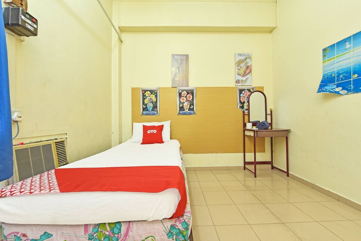 Quarto pequeno e limpo, com uma cama, escrivaninha e cadeira.