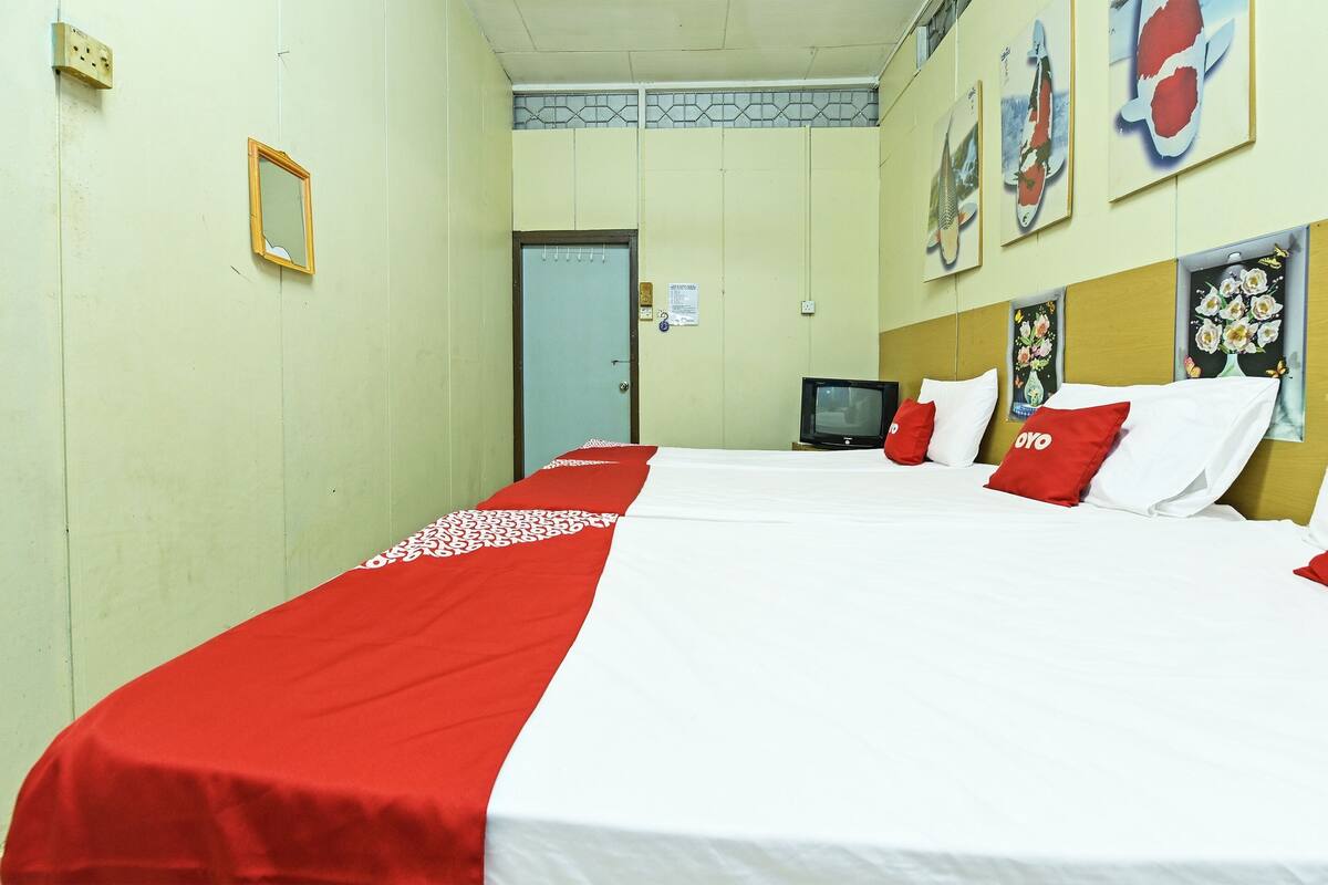 Quarto de hotel com duas camas, televisão e obras de arte nas paredes.