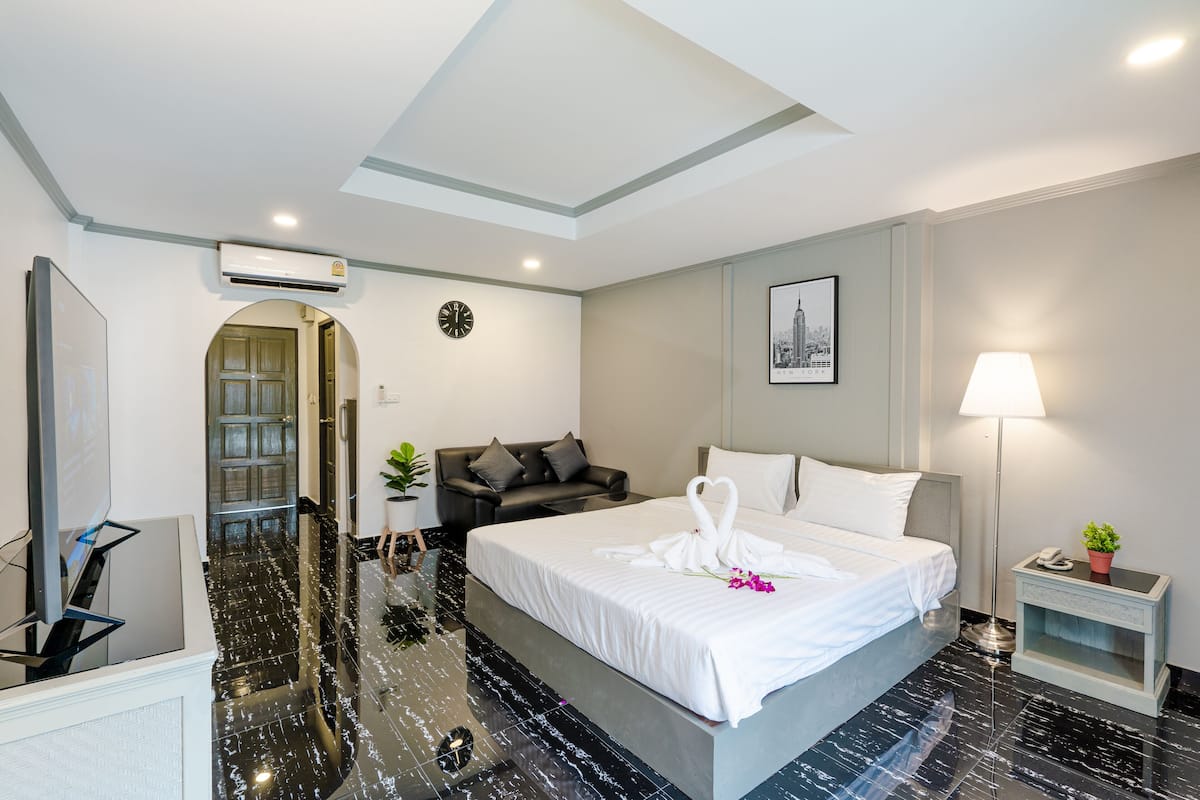 Une chambre d’hôtel moderne équipée d’un grand lit, d’un canapé, d’un bureau et d’un téléviseur à écran plat.