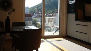 A modern kitchen with a large window, a dining area with a table and chairs, and a view of a hillside. - Modern city apartment (Neustadt an der Weinstraße)