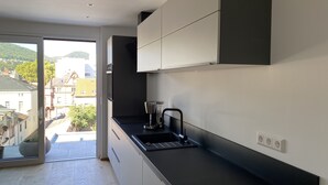 A modern kitchen with a black countertop, white cabinets, and a coffee maker. - Modern city apartment (Neustadt an der Weinstraße)
