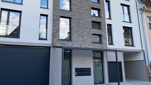 A modern multi-story building with a brick facade, large windows, and a garage entrance. - Modern city apartment (Neustadt an der Weinstraße)