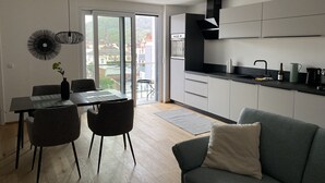 A modern kitchen with a dining area, featuring a large window, a built-in oven, and a black countertop. - Modern city apartment (Neustadt an der Weinstraße)