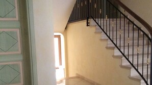 Un escalier avec une rampe noire et des marches blanches menant à l’étage supérieur.