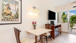 Un comedor con mesa y sillas, un televisor de pared y un cartel de carnaval.