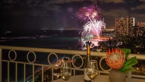 Un balcón con vistas a fuegos artificiales sobre una ciudad costera.