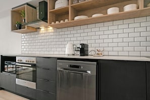 Eine moderne Küche mit eingebautem Ofen, Geschirrspüler und einer Kaffeemaschine auf der Arbeitsfläche.