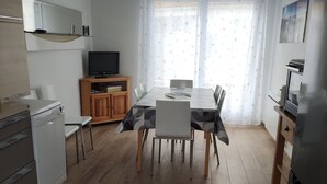 Una cocina moderna con comedor, suelo de madera y televisor.
