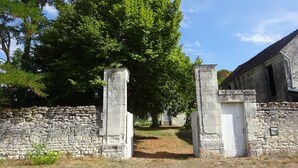 Eine Steinmauer mit einem Tor, das zu einem Gebäude mit einer weißen Tür führt.