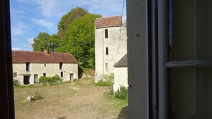 Blick auf einen Innenhof mit Steingebäuden, darunter ein hohes Gebäude mit einem Fenster und ein niedrigeres Gebäude mit mehreren Fenstern.