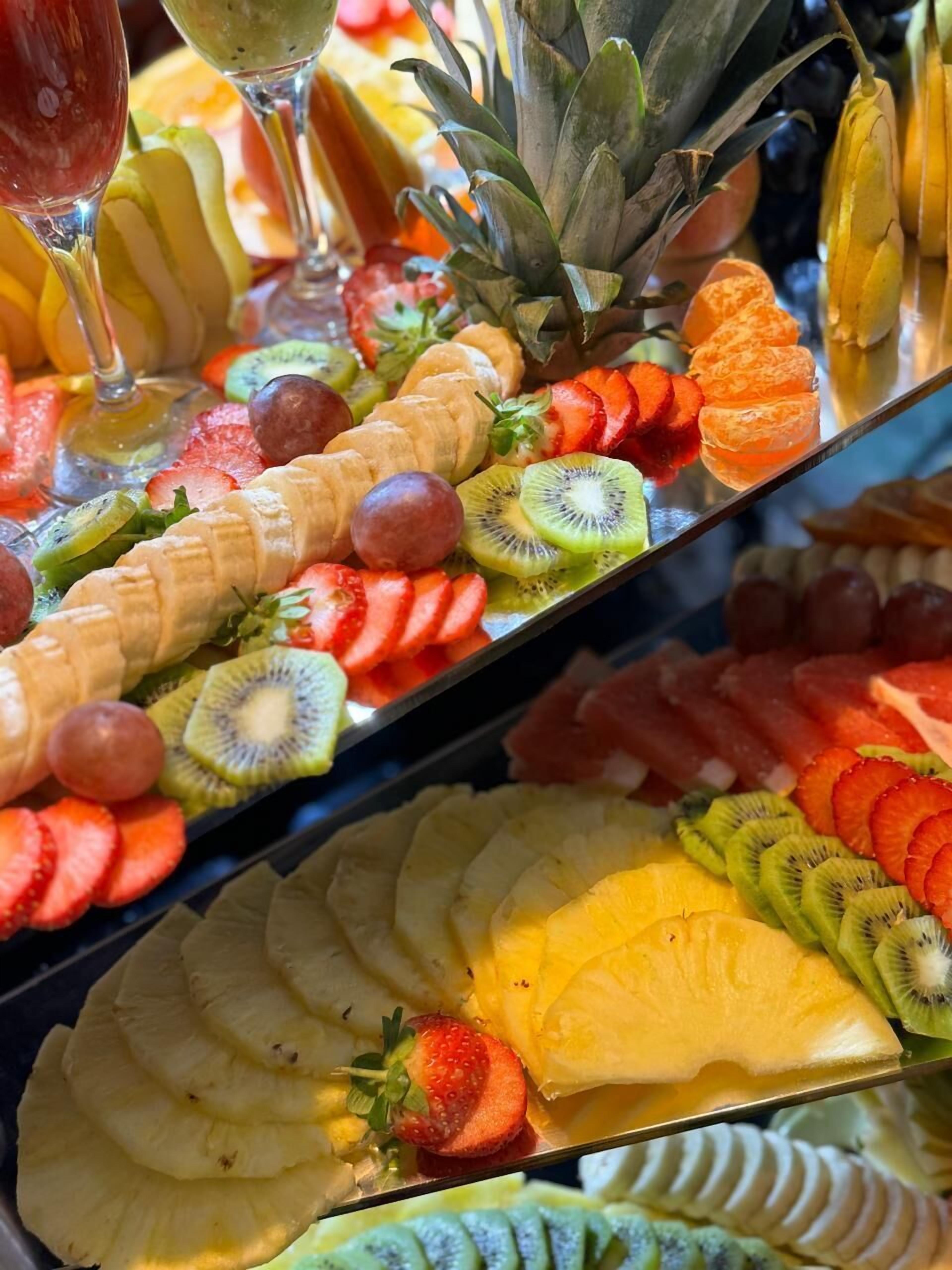 A fruit platter with various fruits including bananas, strawberries, kiwi, pineapple, and grapes.