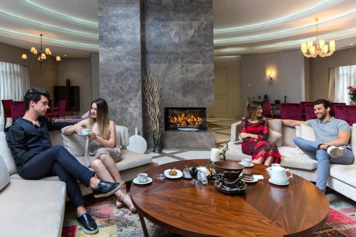 A modern lounge area with a fireplace, comfortable seating, and a coffee table with tea and snacks.