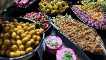 Un bufé con diversos platos, entre ellos aceitunas, verduras encurtidas y carne.