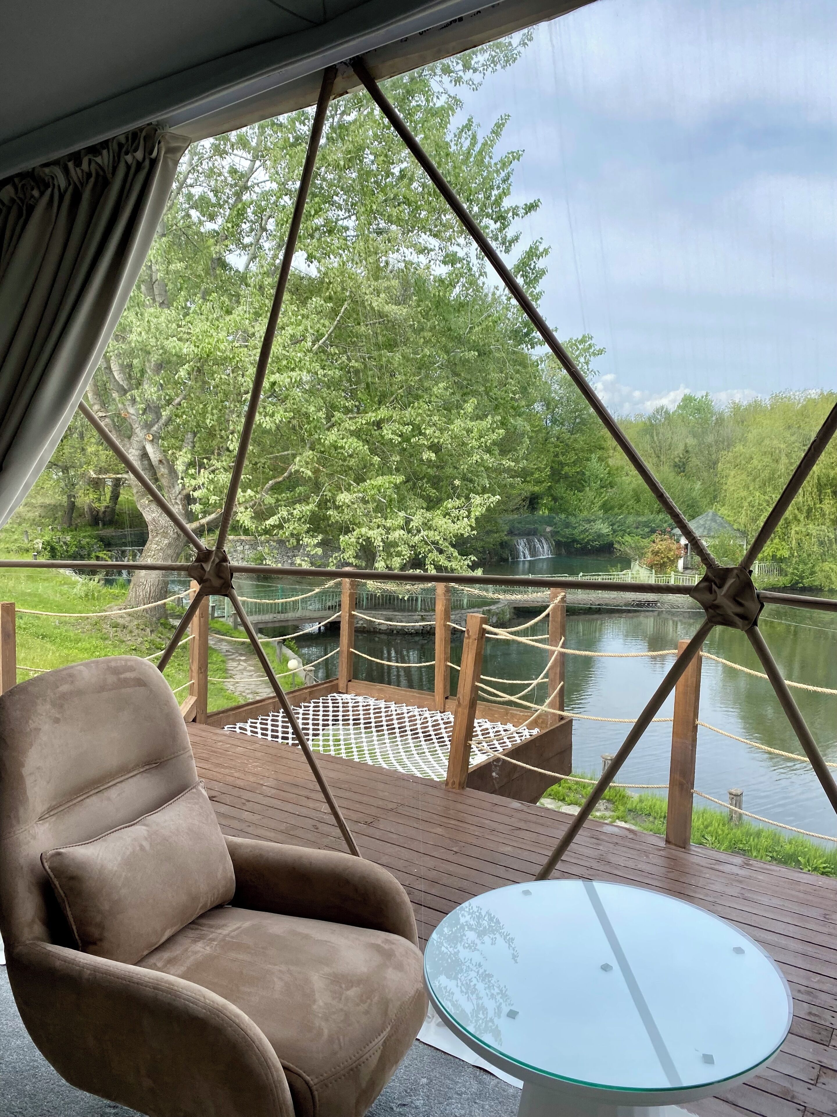 A room with a view of a lake, a rope bridge, and a chair.