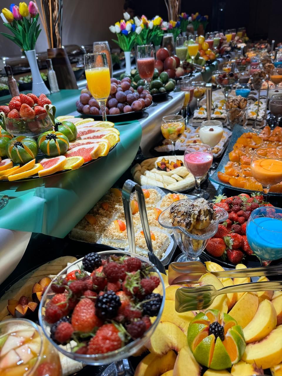 A buffet with a variety of fruits, juices, and desserts.