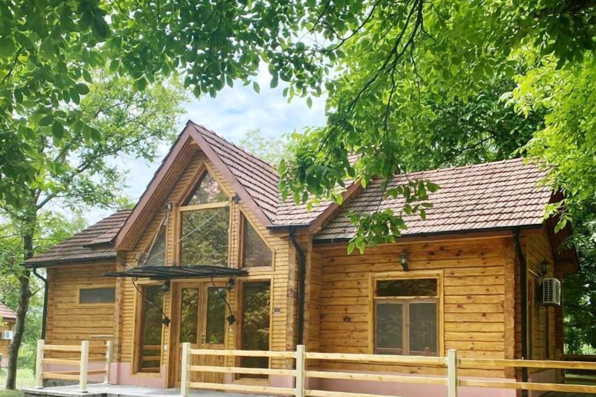 A wooden cabin with a stone foundation, a pitched roof, and a wooden porch with steps.